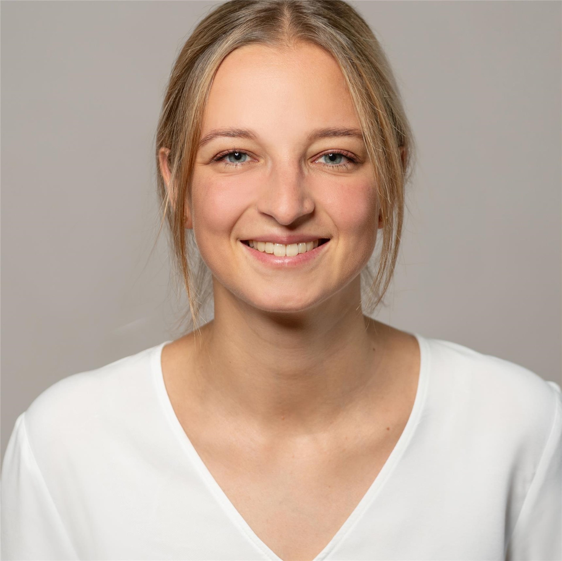 Portrait einer lächelnden Frau vor grauem Hintergrund