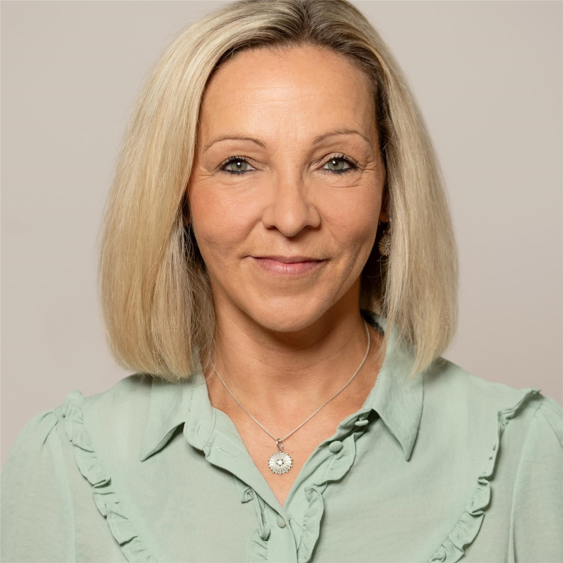 Portrait einer lächelnden Frau vor grauem Hintergrund