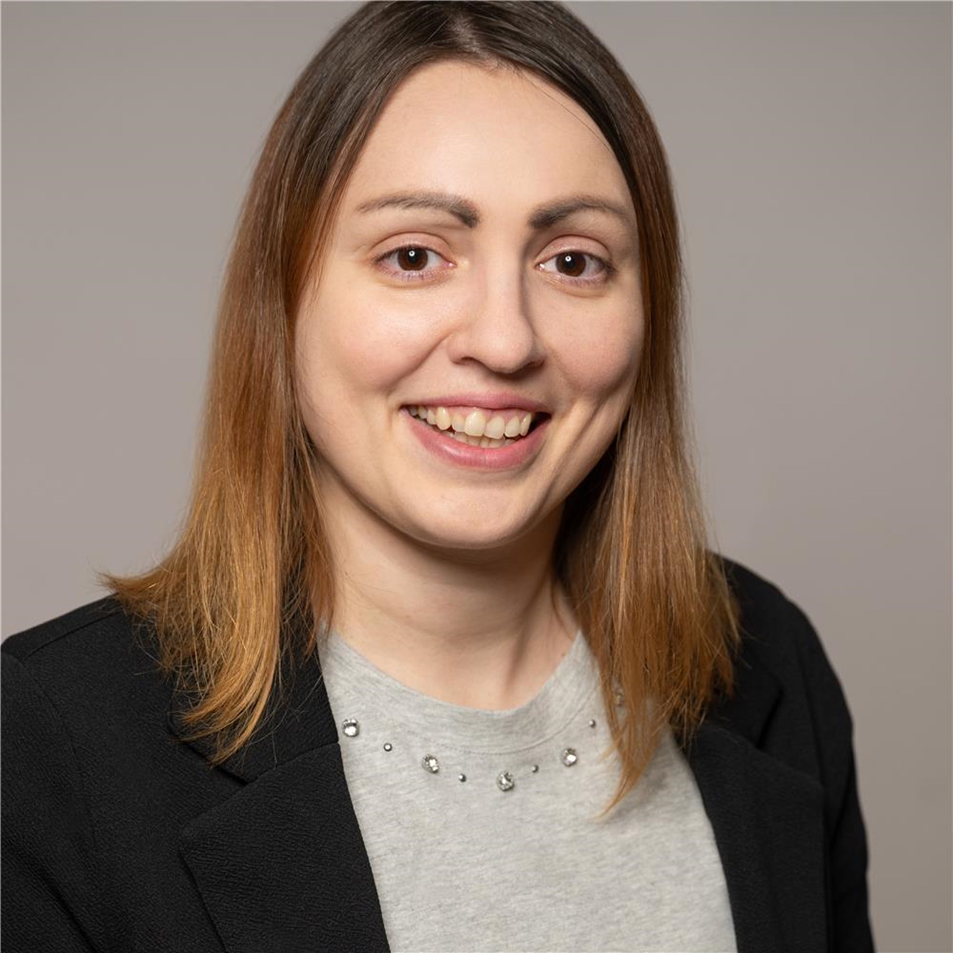 Dilmann, Natali
lächelnde mittelblonde Frau, graues Oberteil mit darüberliegender schwarzer Jacke